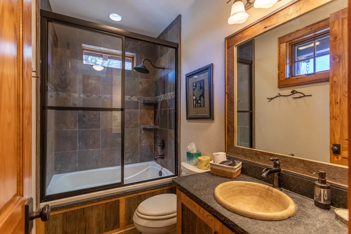 A serene bathroom highlighted by a modern glass shower, a stylish sink with a bowl, and framed artwork. The design is clean, calm, and spa-like, suggesting premium amenities and a soothing atmosphere for unwinding after a day of adventure.